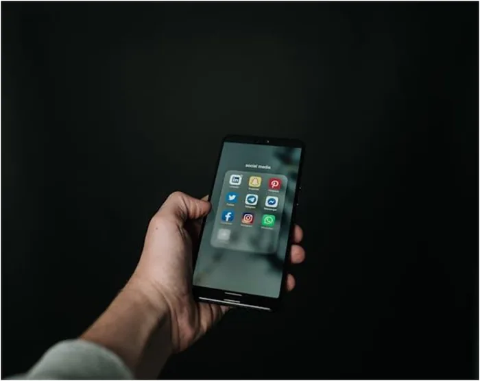 Person holding a phone showing various social media